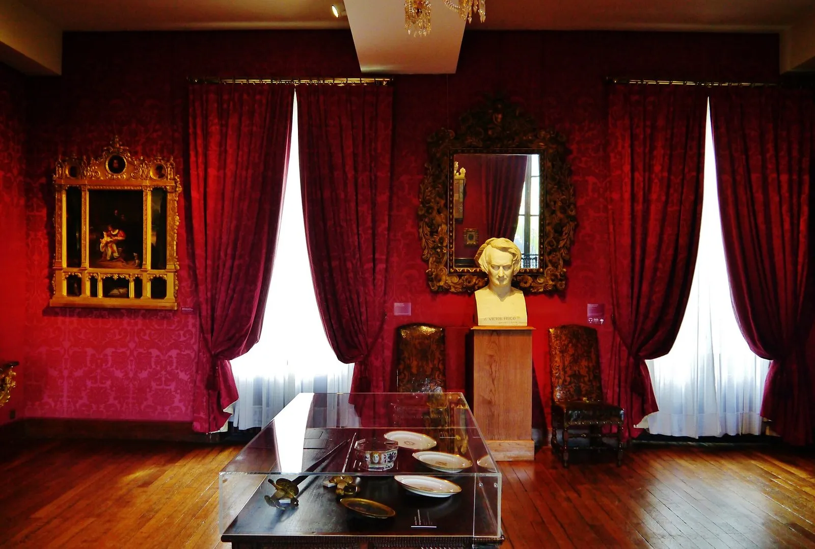 Le salon rouge de l’appartement de Victor Hugo, avec un buste entre les rideaux