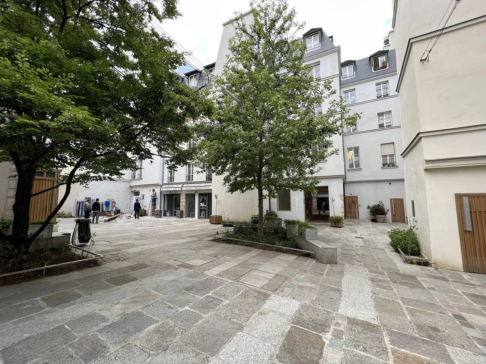 La cour Charles-V du village Saint-Paul, avec sa place pavée et ses arbres