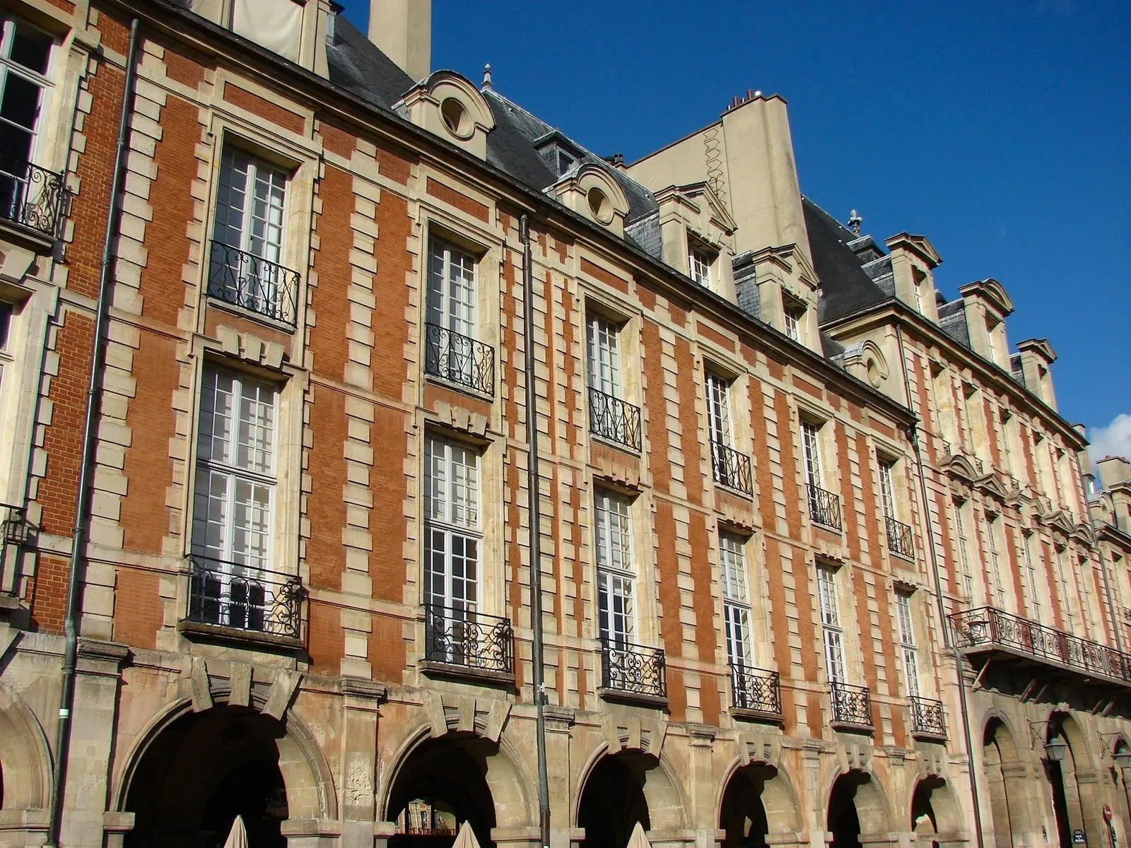 Façade de brique et de pierre et arcades d’un hôtel particulier de la place des Vosges